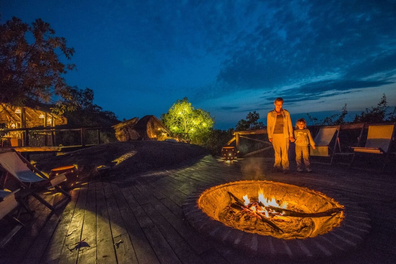 Fire pit glowing on the rock terrace at Maweninga Camp at dusk