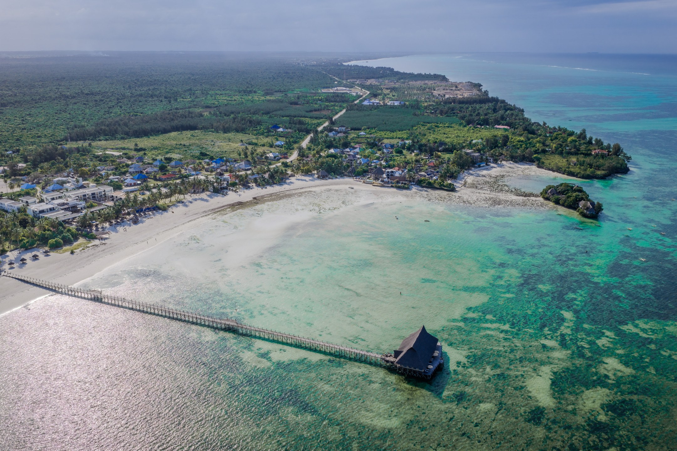 Aerial view of Pongwe Bay at low tide, with sand flats and coral pools exposed either side of the long pier